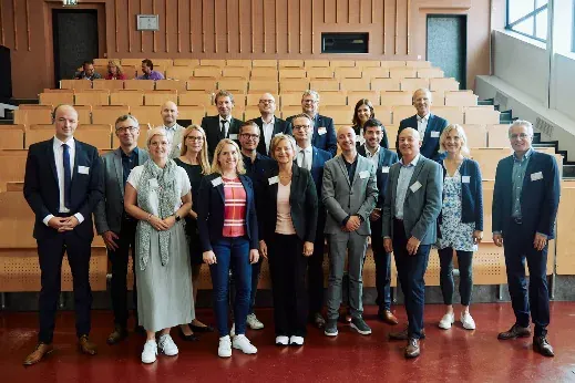 Gruppenbild der Referentinnen und Referenten der Jubiläumstagung vor den Sitzreihen des Hörsaals.