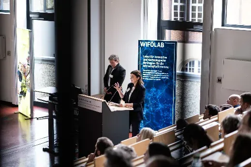 Vortrag im Hörsaal der Hochschule Harz neben dem Roll-up „WiföLAB – Labor für innovative und technologische Strategien für die Wirtschaftsförderung“.