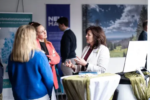 Gespräch in der Tagungspause vor den Ausstellerwänden, im Hintergrund Roll-ups der beteiligten Partner.