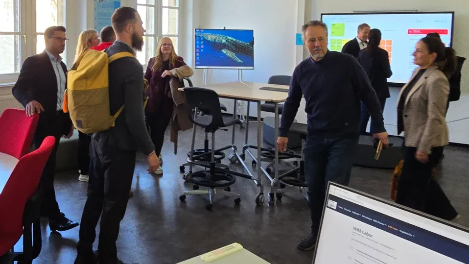 Teilnehmende des Workshops im neuen WiföLAB-Raum der Hochschule Harz, im Hintergrund die Bildschirme der Arbeitsinsel